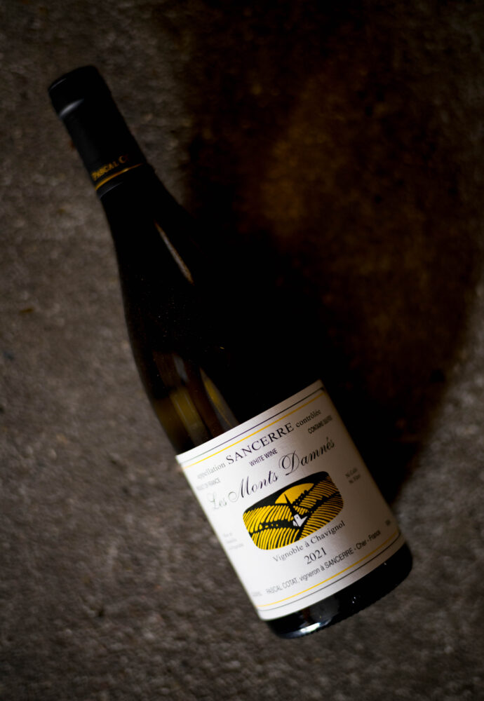 PASCAL COTAT（パスカル・コタ） SANCERRE  LES  MONTS  DAMNÉS（サンセール　レ・モンダネ）2021（2021ヴィンテージ）PASCAL COTAT（パスカル・コタ） SANCERRE  LA  GRANDE  ⅭÔTE（サンセール　ラ・グランド・コート）2021（2021ヴィンテージ）FRANCE　フランス　ＬＯＩＲＥ　ロワール　輸入元　株式会社ミレジム　ＭＩＬＬÉＳＩＭＥＳ　届けたいのはブランドではなく、造り手の魂の結晶です。　
「コタが造るものより偉大なサンセールはない」ロバート・パーカー
ソーヴィニヨン・ブラン発祥の地ロワール。その中心となるサンセールにドメーヌを構え、世界中のソーヴィニヨン・ブラン生産者の目標なってい最高の造り手がパスカル・コタです。パスカルとフランソワは従兄同士で、2人の父親は共同でドメーヌを運営していました。その伝統的な造りをそのまま引き継いでいるため、ワインの味わいに大きな差はなく、ラベルも瓜ふたつです。パスカル・コタのサンセールは、サンセールがいかに素晴らしいかをよく表しています。今では既にここの地域では当たり前となっていますが、単一畑のブドウからワインを造ったのはコタが初めてでしたし、最初に無濾過で瓶詰めしたのもコタでした。畑はサンセールの最良の区画の1つに挙げられ、手作業でないと作業ができないほどの急斜面に位置します。この地形と自然環境を生かし、ビオデイナミ農法が話題となる以前から、有機農法や古典的な醸造を続けていきました。収穫は完熟を持って遅摘みし、全て手作業で収穫・選果します。古典的なバスケット・プレス（高級シャンパン・ハウスで使用されているものと同じもの）を使用し、人力で圧搾します。これは非常に穏やかな圧搾工程で、質の高いマストが得られます。ワインは全て樽発酵させていますが、独特の醸造技術で樽を感じさせない円やかな味わいを引きだしています。マロラティック発酵、濾過処理はせず、、月の満ち欠けに合わせて瓶詰めします。こういった様々な努力により長期熟成に耐える卓越したワインを生み出します。サンセールが熟成するかどうか議論になる時、ソーヴィニヨン・ブランが非常に良く熟成する最高の例として、決まってコタのワインが引き合いに出されます。ロバート・パーカーが「私が口にしたことのある最良のソーヴィニヨン・ブランの1つ」と評するほど素晴らしいワインを産出しています。コタのワインは、ミネラル感とフレッシュな爽快感に溢れつつも、ふくよかな果実味が感じられ、メロンやミントを思わせる爽やかなアロマが香ります。サンセールが早飲みの白ワインという固定概念を覆させる逸品です。パスカル・コタの収穫は、サンセールの生産者の中でも最も遅く、この遅い収穫こそ、シャプタリゼーションを一切せずとも非常に高い残糖量を出すことの出来る秘訣です。フランソワとは対照的に、パスカルは極めて遅めの収穫を好みます。将来、この点がフランソワ・コタとパスカル・コタの違いを語る上で重要なポイントとなり得るかもしれません
